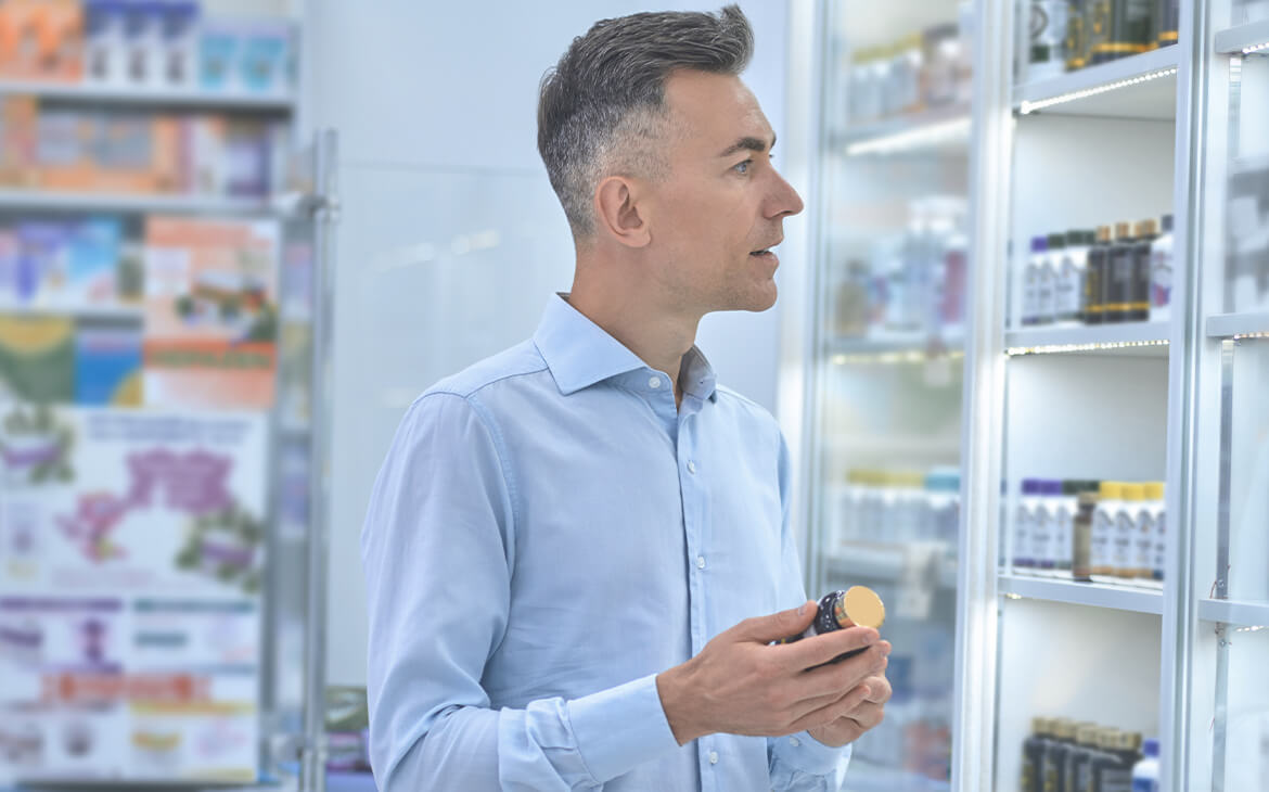 Homem adulto de aproximadamente 40 anos analisando uma gondola de farmácia